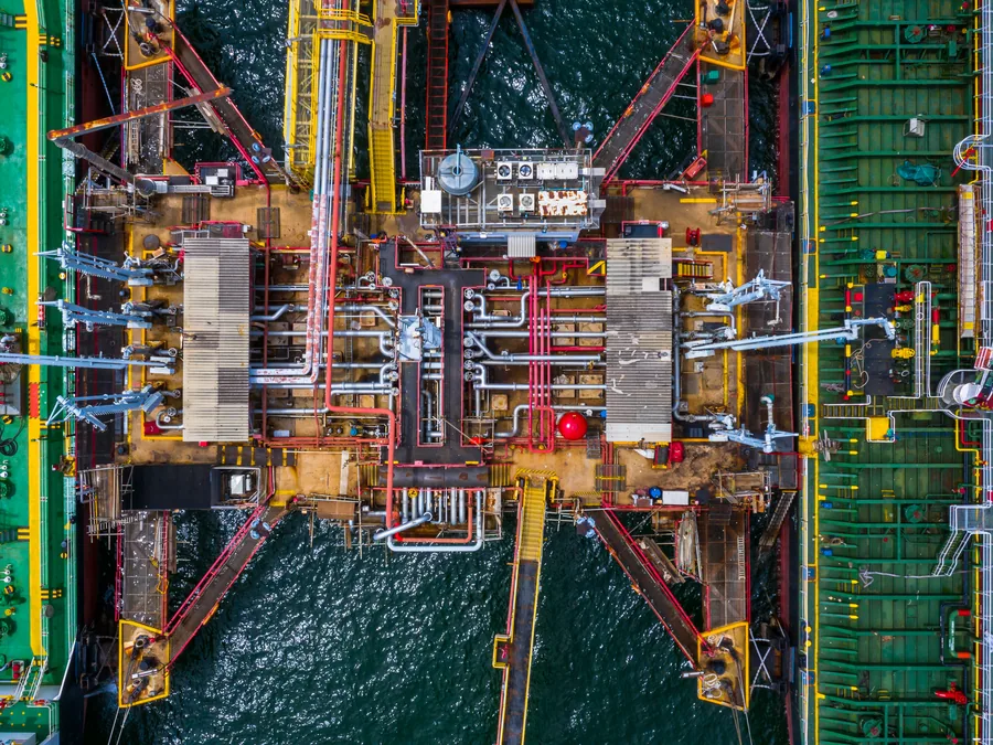 Aerial view of a tanker's cargo manifold and loading arms alongside a terminal.