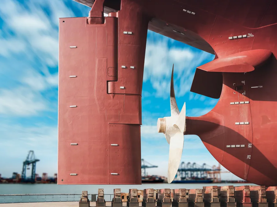 Rudder and propeller exposed above the waterline at a repair berth.