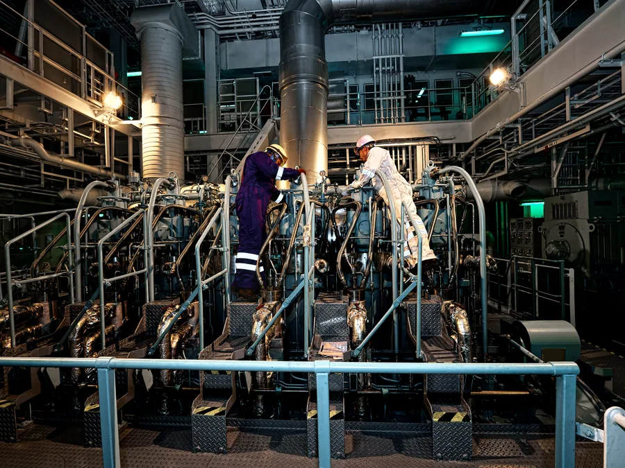 Engineers working on the main engine platform during maintenance on board.