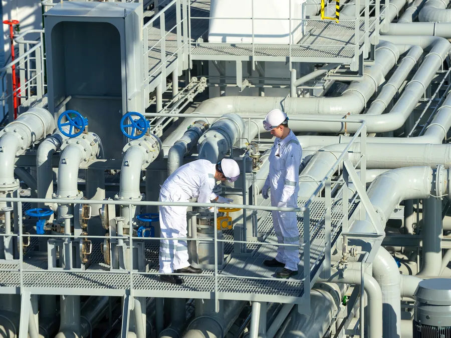 Two inspectors examining deck pipework and valves on a chemical tanker.